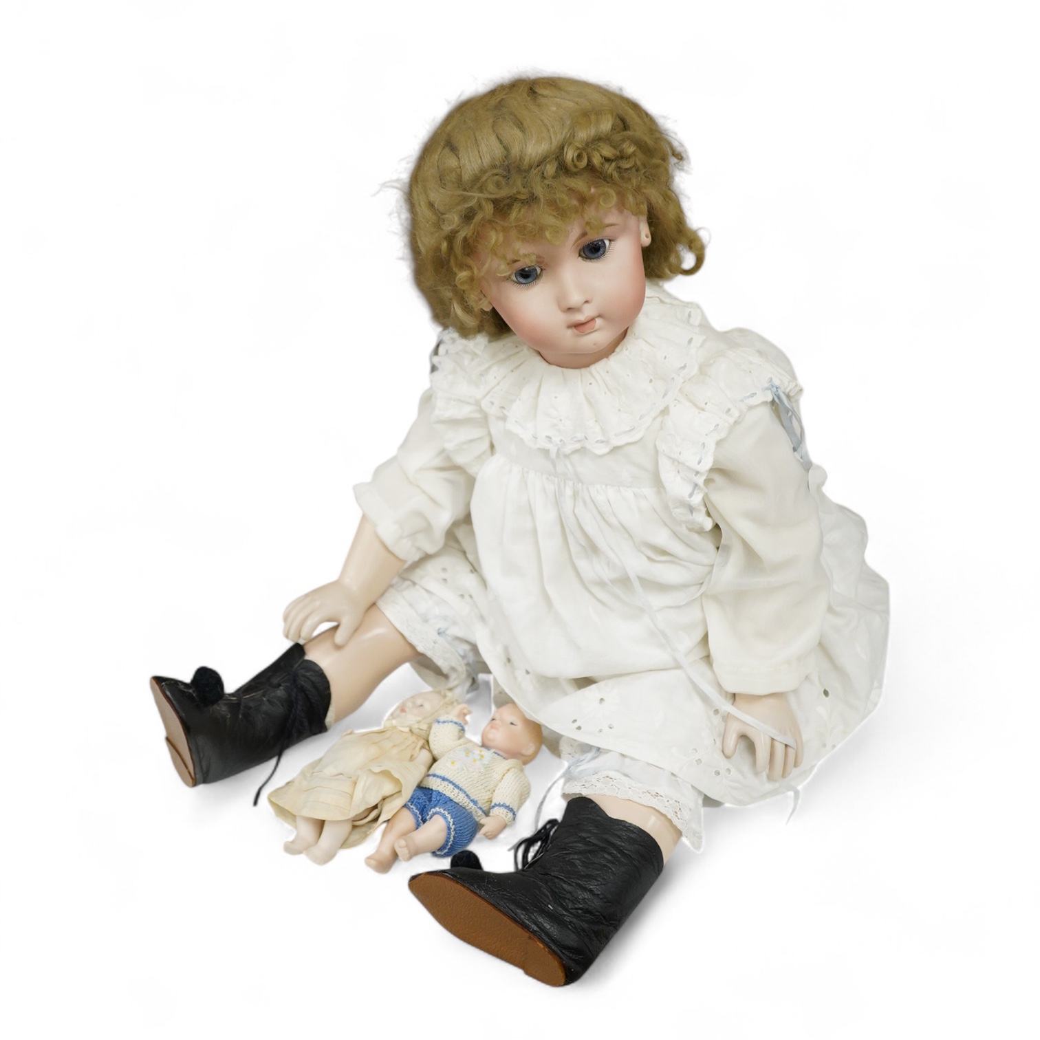 A large jointed bisque head doll and two miniature bisque dolls